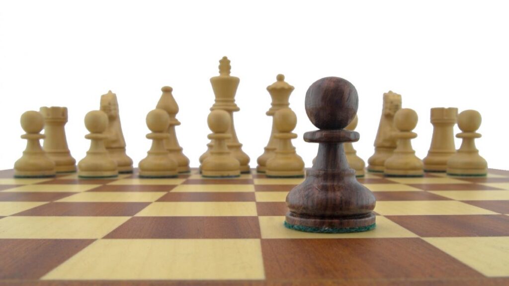 Peón negro de ajedrez sobre tablero, con todas las piezas blancas
